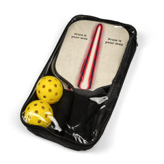 A black zippered carrying case holds two wooden pickleball paddles with a red and white stripe design, and two yellow pickleballs.