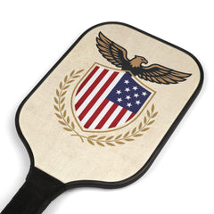 Close-up angled view of the wooden pickleball paddle face showing the detailed eagle, stars and stripes shield, and laurel wreath.