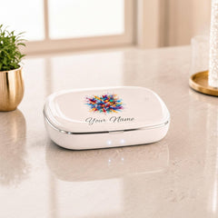 A white UV sanitizer box with its lid open sits on a white surface next to a white vase and a framed picture.